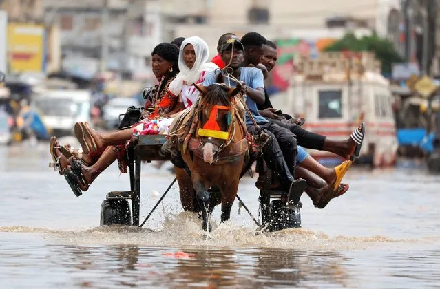 Residents make their way through a flooded street after heavy rains in Yoff, district of Dakar, Senegal on July 20, 2022. (Photo by Zohra Bensemra/Reuters)