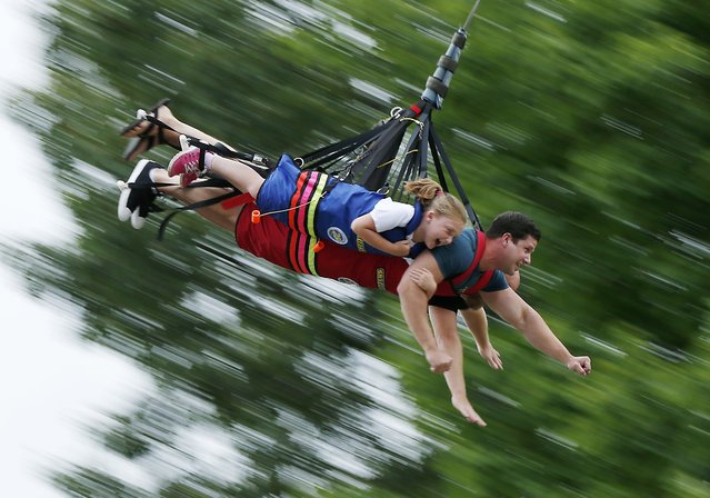 Lilly Caron, 8, of Bridgeton, Maine, Jason Homchick, of San Diego, and Lilly's father Jason Caron, (obscured), ride the Sky Swing at Seacoast Adventure, Thursday, July 14, 2016, in Wyndham, Maine. The 100-foot-tall swing gives riders the combined thrills of sky diving and hang gliding. (Photo by Robert F. Bukaty/AP Photo)