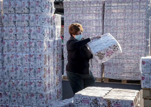 A woman piles up toilet paper at a a “toilet paper drive in” on a parking spot in Dornburg, some 60 km west of Frankfurt, Germany, Wednesday, April 1, 2020. After panic buying due to the coronavirus outbreak toilet paper has become rare and the owner of a pet food shop was able to order thousands of rolls of toilet paper which he sells now outside of his shop. (Photo by Michael Probst/AP Photo)