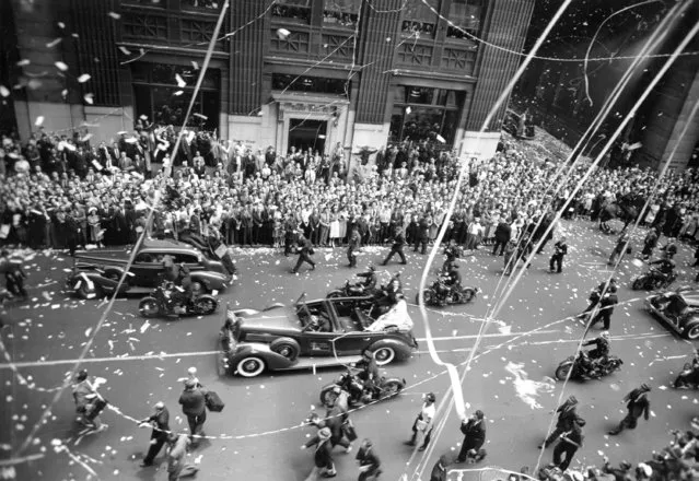 Howard Hughes waves to the crowd from the back seat of an open car, center, during a welcome parade for the aviator along Broadway in lower Manhattan, July 15, 1938.  Hughes and his crew arrived yesterday after completing a flight around the world in less than four days. (Photo by AP Photo)