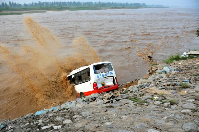 An abandoned bus filled with sand bags is used to build a makeshift dike at a flooded area in Xingtai, Hebei Province, China, July 21, 2016. (Photo by Reuters/Stringer)