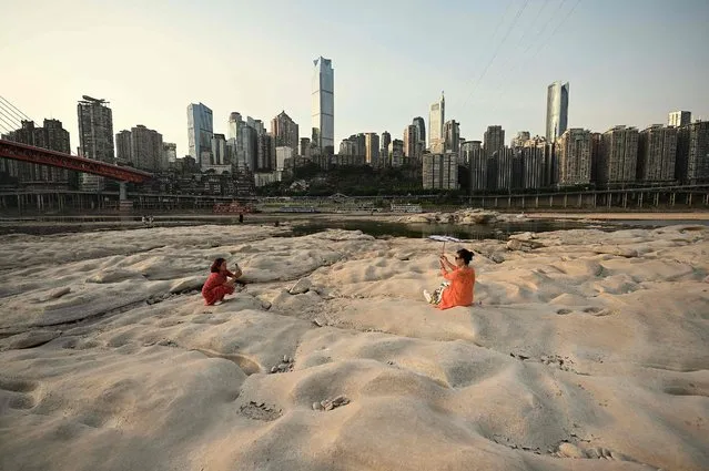 People are seen at the dried-up riverbed of the Jialing river, a tributary of the Yangtze River in China's southwestern city of Chongqing on August 25, 2022. (Photo by Noel Celis/AFP Photo)