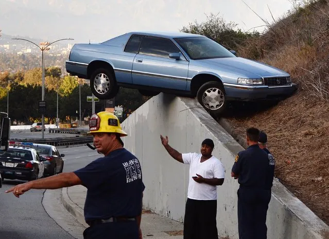 A car sits atop an embankment after losing control and skidding up the concrete retaining wall on South La Brea Ave in Baldwin Hills, Los Angeles on August 24, 2014. The driver and his passenger escaped injury. (Photo by Mark Ralston/AFP Photo)