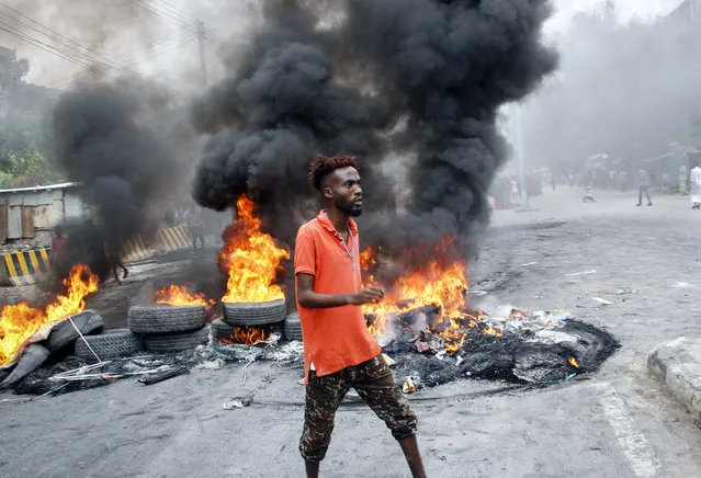 A Somali man protests against the killing Friday night of at least one civilian during the overnight curfew, which is intended to curb the spread of the new coronavirus, on a street in the capital Mogadishu, Somalia Saturday, April 25, 2020. A police officer in Somalia's capital has been arrested in the fatal shooting of at least one civilian while enforcing coronavirus restrictions, a fellow police officer said, sparking protests that continued Saturday with crowds of angry young men burning tires and demanding justice. (Photo by Farah Abdi Warsameh/AP Photo)