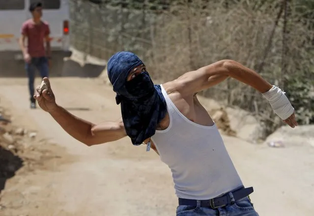 A masked Palestinian throws stones during a protest against what organizers say is land confiscation by Israel to make way for the Israeli barrier in the occupied West Bank city of Beit Jala, near Bethlehem September 6, 2015. (Photo by Mussa Qawasma/Reuters)