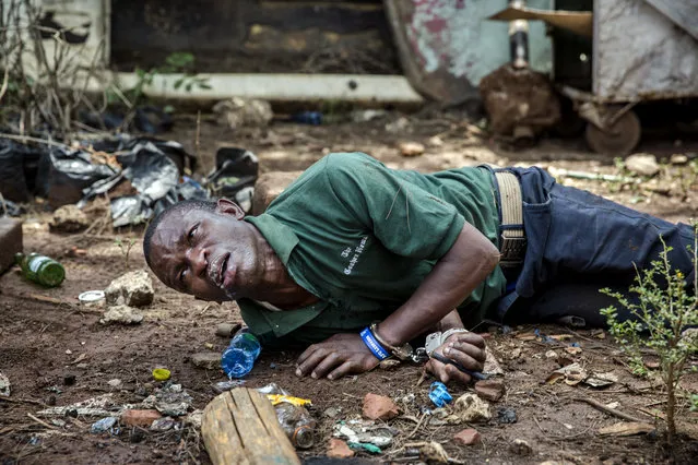 A protester seriously affected by tear gas and allegedly beaten up by police officers lays on the ground with handcuffs on after being arrested in Uhuru Park in Nairobi, on October 13, 2017. Hundreds of opposition supporters took to the streets of Kenya's main cities on October 13 in defiance of a government ban on protests as the country is gripped by uncertainty over its presidential election. (Photo by Luis Tato/AFP Photo)