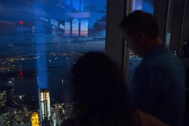 People peer through the windows at One World Observatory, the observation deck at One World Trade Center, as the Tribute in Light installation shines in Lower Manhattan in New York September 11, 2015. (Photo by Andrew Kelly/Reuters)