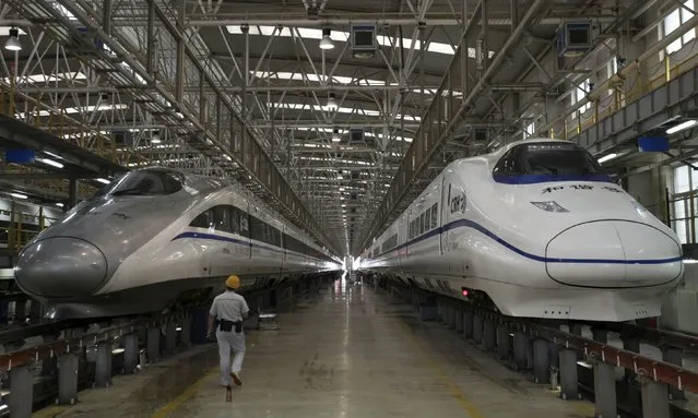 A worker walks between two bullet trains at a high speed railway maintenance station in Xi'an, Shaanxi province, China, September 10, 2015. China will strengthen fiscal policy, boost infrastructure spending and speed up reform of its tax system to support the economy, the Ministry of Finance said, joining other steps by authorities to re-energize sputtering growth. (Photo by Reuters/Stringer)