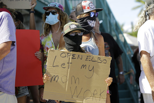 Bartender Kat DeLaTorre stands with her son Nico, 12, during a “Right to Work” rally outside of the Elbo Room bar, which remains closed, during the new coronavirus pandemic, Tuesday, June 16, 2020, in Fort Lauderdale, Fla. Across Florida, bars were part of the Phase 2 reopenings that occurred earlier in June, except in three counties in South Florida. (Photo by Lynne Sladky/AP Photo)