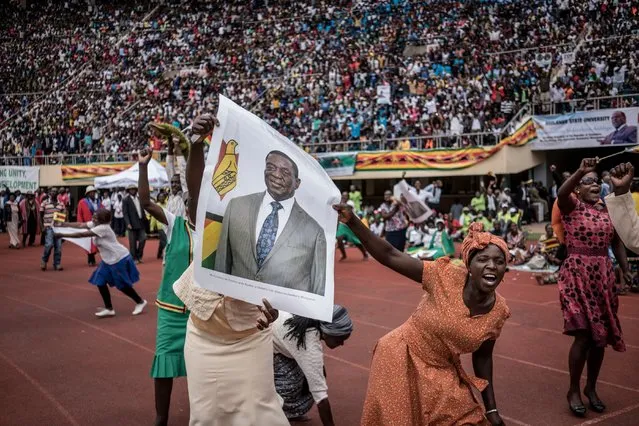 Supporters hold poster of the newly sworn-in President Emmerson Mnangagwa during the Inauguration ceremony at the National Sport Stadium in Harare, on November 24, 2017. Zimbabwe's newly sworn-in President Emmerson Mnangagwa vowed during his inauguration speech on November 24 to protect foreign investments in the country as he sought to lay out his economic credentials. "In this global world no nation is, can, or need be an island. All foreign investments will be safe in Zimbabwe," he told a crowd of tens of thousands at his inauguration ceremony. (Photo by Marco Longari/AFP Photo)