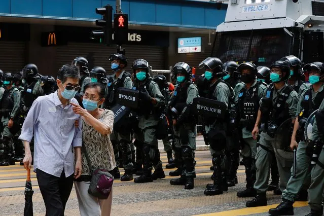 A couple walks past riot police as anti-national security law protesters march during the anniversary of Hong Kong's handover to China from Britain, in Hong Kong, China on July 1, 2020. (Photo by Tyrone Siu/Reuters)