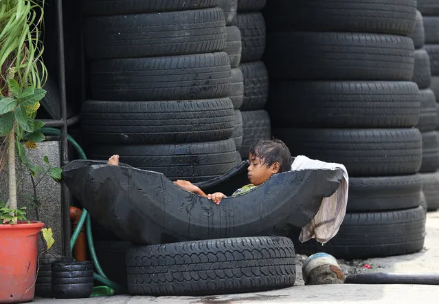 A Filipino girl takes a dip in a tire used at a vulcanizing shop in suburban Manila, Philippines on Friday, July 22, 2016. Many Filipinos still resort to buying used tires to save money. (Photo by Aaron Favila/AP Photo)