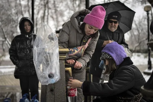 People collect water, in Kyiv, Ukraine, Thursday, November 24, 2022. (Photo by Evgeniy Maloletka/AP Photo)