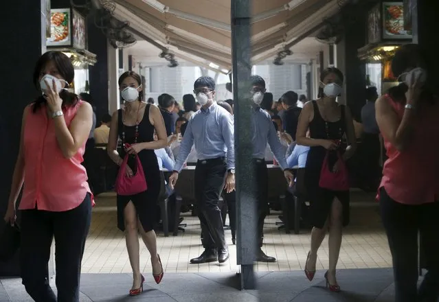 Office workers wearing masks walk during lunch hour at the central business district in Singapore September 29, 2015. (Photo by Edgar Su/Reuters)