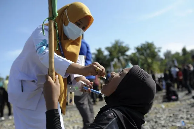 A medical worker gives drops of vaccine to a girl during a polio immunization campaign at Sigli Town Square in Pidie, Aceh province, Indonesia, Monday, November 28, 2022. Indonesia has begun a campaign against the poliovirus in the the country's conservative province after several children were found infected with the highly-contagious disease that was declared eradicated in the country less than a decade ago. (Photo by Riska Munawarah/AP Photo)