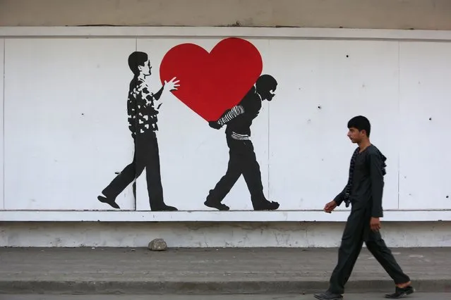 In this Thursday, August 20, 2015, photo, an Afghan boy walks in front of street art on a barrier wall of the NDS (National Directorate of Security) in Kabul, Afghanistan. (Photo by Rahmat Gul/AP Photo)