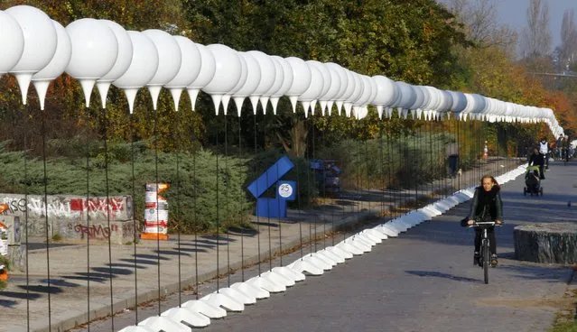 A woman cycles along stands with balloons placed along the former Berlin Wall location at Mauerpark, which will be used in the installation “Lichtgrenze” (Border of Light) in Berlin November 7, 2014. (Photo by Pawel Kopczynski/Reuters)