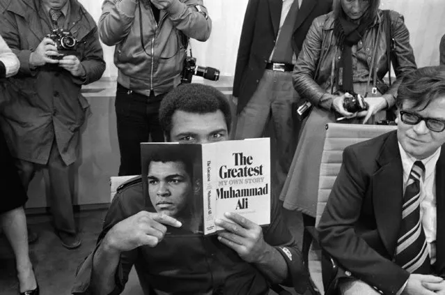Muhammad Ali peers over a copy of his book "The Greatest," in the VIP room at the airport in Frankfurt, October 10, 1975. Ali came to Frankfurt to introduce his book at the International Book Fair. (Photo by Kurt Strumpf/AP Photo)