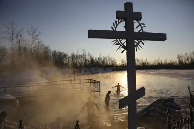 People bath in water during a traditional Epiphany celebration as the temperature dropped to about –14 degrees (10,4 degrees Fahrenheit) near the Achairsky monastery outside the Siberian city of Omsk, Russia, early Thursday, January 19, 2023. Across Russia, the devout and the daring are observing the Orthodox Christian feast day of Epiphany by immersing themselves in frigid water through holes cut through the ice of lakes and rivers. Epiphany celebrates the revelation of Jesus Christ as the incarnation of God through his baptism in the River Jordan. (Photo by Evgeniy Sofiychuk/AP Photo)