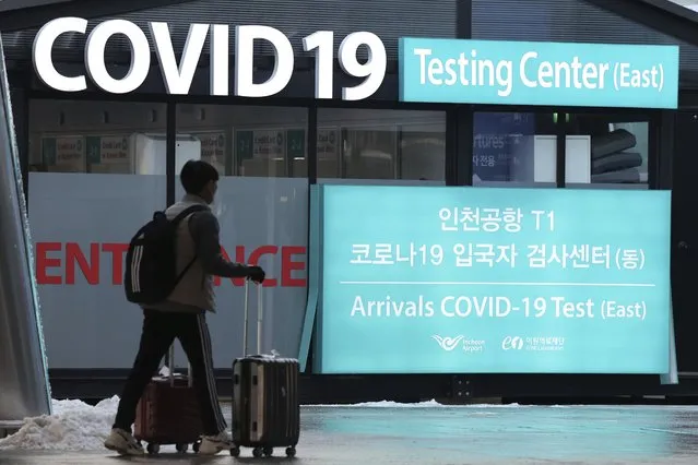 A traveler walks near a banner for the coronavirus testing center at the Incheon International Airport in Incheon, South Korea, Friday, December 30, 2022. South Korea on Friday announced that it will require travelers from China to show negative PCR test results within 48 hours or rapid antigen tests within 24 hours of their departures, beginning Jan. 5. (Photo by Ryu Young-suk/Yonhap via AP Photo)