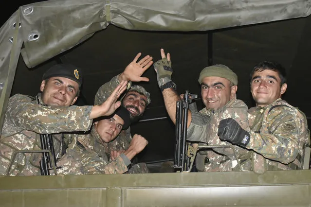 In this photo released on Tuesday, October 6, 2020, Armenian soldiers wave to a photographer as they sit in a truck during fighting with Azerbaijan's forces in self-proclaimed Republic of Nagorno-Karabakh, Azerbaijan, Sunday, Oct. 4, 2020. The clashes have continued despite numerous international calls for a cease-fire. (Photo by Press office of Armenian Defense Ministry PAN Photo via AP Photo)