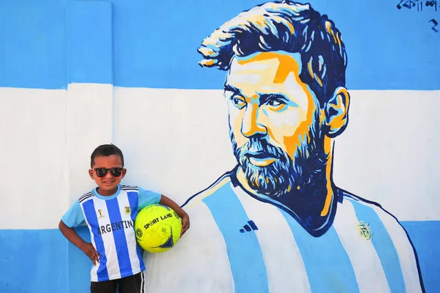 A young Argentina fan poses in front of a mural of his hero, Lionel Messi, ahead of the World Cup quarter-final against the Netherlands in Sylhet, Bangladesh on December 10, 2022. (Photo by Md Rafayat Haque Khan/ZUMA Press Wire/Rex Features/Shutterstock)