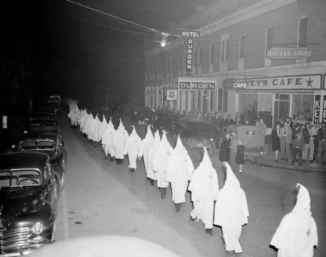 Members of the Ku Klux Klan, wearing traditional white hoods and robes, march in single file around the town square in Swainsboro, Ga., February 3, 1948.  The Klansmen made their way to the Emanuel County Courthouse lawn where they burned a cross. (Photo by AP Photo)