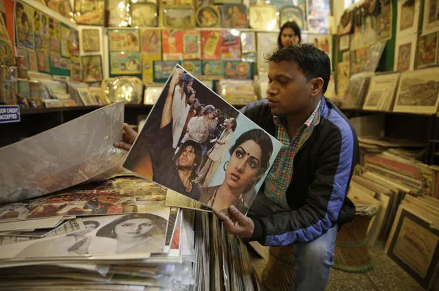 An Indian shopkeeper who sells Bollywood posters and movie stills holds a poster featuring Sridevi and Amitabh Bachchan in New Delhi, India, Wednesday, February 28, 2018. Thousands of grieving fans gathered in Mumbai on Wednesday to pay respects to Sridevi, the iconic Bollywood actress who drowned accidentally in a Dubai hotel bathtub over the weekend. (Photo by Altaf Qadri/AP Photo)