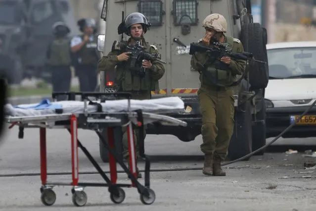 Israeli security forces secure the area where a Palestinian woman Tharwat Sharawi, 73, was shot and killed in the West Bank city of Hebron, Friday, November 6, 2015. Israeli soldiers shot and killed Sharawi at a West Bank gas station Friday in what the Israeli military alleged was an attempt by her to attack them with her car. (Photo by Nasser Shiyoukhi/AP Photo)