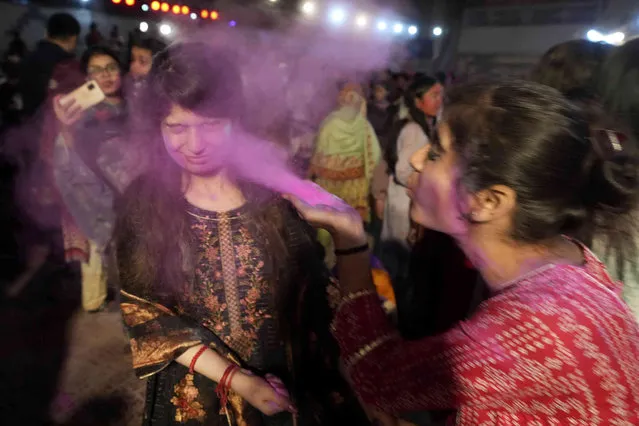 A girl from the Pakistani Hindu community blows color to the face of her friend to celebrate the Holi Festival, in Karachi, Pakistan, Monday, March 6, 2023. Holi Festival marks the beginning of spring and the triumph of good over evil. (Photo by Fareed Khan/AP Photo)