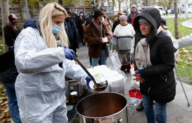 A Romanian volunteer woman (L), wearing protective outfit, serves a free hot meal to a homeless elderly woman (R), during a charity event named “Under the clear sky” organized by an NGO called “Interleaved” , in downtown Bucharest, Romania, 03 December 2020. Romania goes to the polls on 06 December to elect a new parliament despite Covid pandemic. (Photo by Robert Ghement/EPA/EFE/Rex Features/Shutterstock)