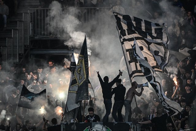 Angers' supporters wave flags and cheer their team during the French L1 football match between SCO Angers and AS Monaco at the Stade Raymond-Kopa in Angers on October 18, 2025. (Photo by Sebastien Salom-Gomis/AFP Photo)