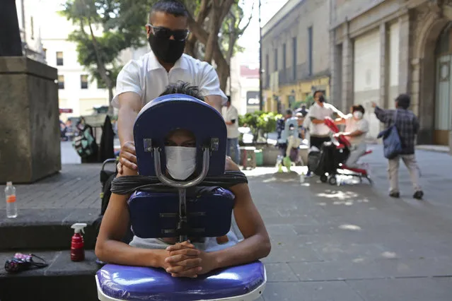 Roberto is getting a massage in the street in Mexico City, Saturday, December 18, 2020. After months of resisting to avoid hurting the economy, officials banned all non-essential activities starting Saturday and returned to a partial lockdown in Mexico City and the surrounding State of Mexico because of a spike in coronavirus cases that has crowded hospitals. (Photo by Ginnette Riquelme/AP Photo)