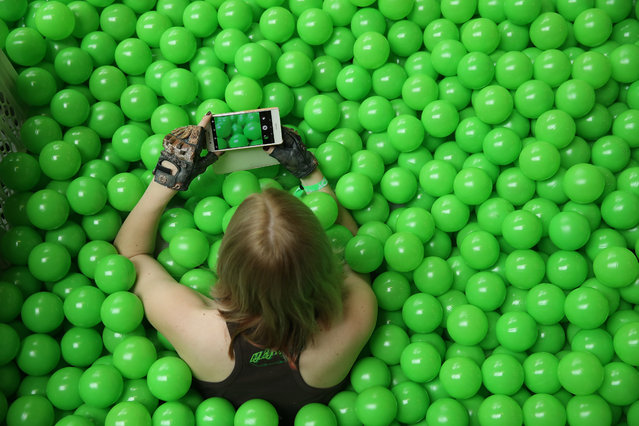 A participant uses her smartphone to photograph the green plastic balls pool she is sitting in at the annual re:publica conferences on their opening day on May 2, 2018 in Berlin, Germany. Re:publica 18 is holding a series of conferences themed with digital society on topics such as media, entertainment, politics, culture and technology from May 2-4. (Photo by Sean Gallup/Getty Images)