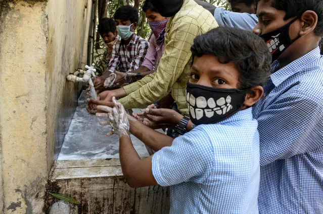 Students wearing facemasks wash their hands before attending a class at a governement-run high school in Secunderabad, the twin city of Hyderabad, on March 4, 2020, as part of health measures taken against the COVID-19 coronavirus outbreak. The new coronavirus that emerged in a Chinese market at the end of last year has killed 2,981 with more than 80,200 people infected in total, the National Health Commission said. (Photo by Noah Seelam/AFP Photo)