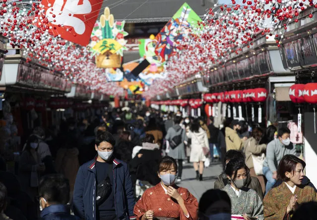 People wearing face masks to help curb the spread of the coronavirus visit Sensoji temple on New Year's Eve in Tokyo Thursday, December 31, 2020. On the New Year's Eve, the shopping street is crowded by last minute shoppers who look for ingredients for “osechi” or Japanese traditional New Year dishes. (Photo by Hiro Komae/AP Photo)