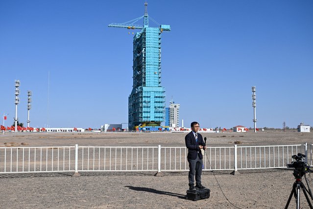 A member of the media is seen in front of the Long March-2F carrier rocket, carrying the Shenzhou-21 spaceship, encased in blue scaffolding on the launch pad a day before the launch of the Shenzhou-21 mission, at the Jiuquan Satellite Launch Centre in the Gobi desert in northwest China on October 30, 2025. (Photo by Héctor Retamal/AFP Photo)