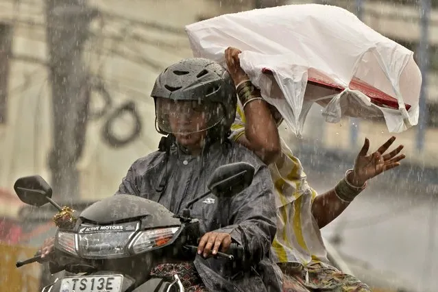Two women ride on a scooter during pre-monsoon rains in Hyderabad, India, Monday, May 1, 2023. (Photo by Mahesh Kumar A./AP Photo)