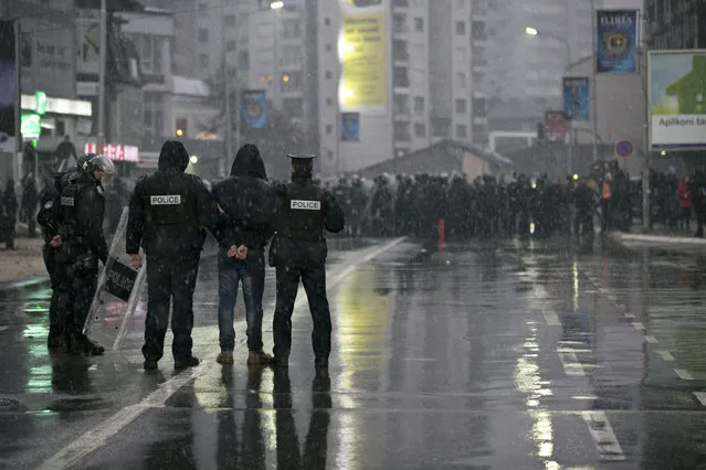 Kosovo police officers in riot gear detain a supporter of the opposition party during a police raid at the Self-Determination party headquarters in Kosovo capital Pristina on Saturday, November 28, 2015. Kosovo lawmaker Albin Kurti from the Self-Determination party and several party members were detained by police after tens of thousands of Kosovo opposition supporters protested against the deals with Serbia and Montenegro. (Photo by Visar Kryeziu/AP Photo)