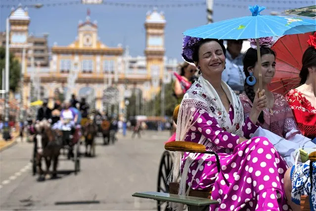 Women ride on a horse carriage sheltering under a sun umbrella at the annual traditional April Fair in Seville, Spain, Thursday, April 27, 2023. Spain's national weather service said temperatures would “reach values typical of summer” across most of the country, with a high of 38 degrees Celsius (100 degrees Fahrenheit) forecast Thursday for the southern Guadalquivir Valley. (Photo by Santi Donaire/AP Photo)