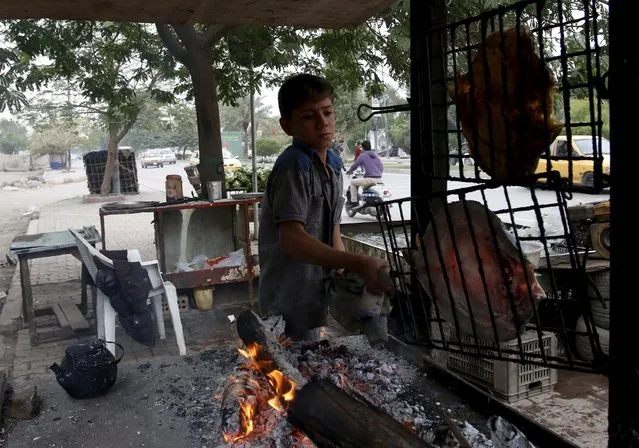 9-year-old Hussain Madhlom sells traditionally cooked grilled fish called "Masgoof", along a sidewalk in Baghdad, November 16, 2015. (Photo by Khalid al-Mousily/Reuters)