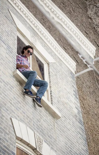 A person interacts with a large-scale installation art piece by Leandro Erlich, named “Dalston House”, is displayed on June 24, 2013 in London, England. Part of the “Beyond Barbican” summer series of events, the interactive installation is a full facade of a late nineteenth-century Victorian terraced house built on the ground with a large mirror above it to reflect people as to appear dangling from the structure.  (Photo by Dan Dennison/Getty Images)