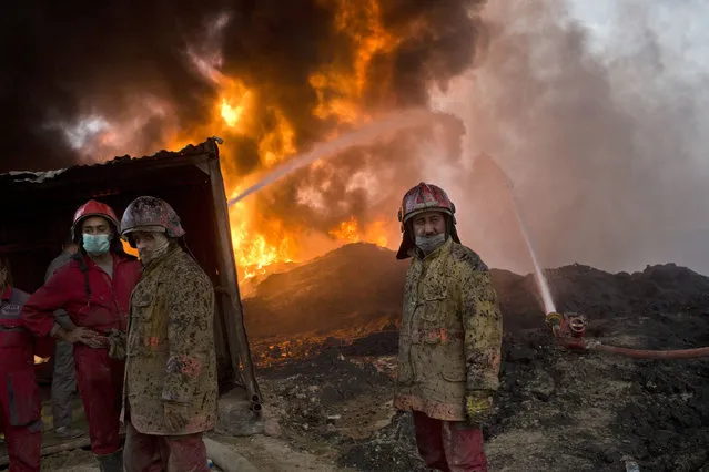 Firefighters work at the site of an oil well fire in Qayara, some 31 miles (50 km) south of Mosul, Iraq, Wednesday, November 9, 2016. Iraqi firefighters worked to extinguish flaming oil wells, set alight by Islamic State militants to reduce visibility. (Photo by Marko Drobnjakovic/AP Photo)