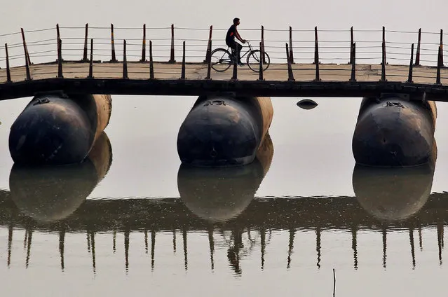 A cyclist crosses a temporary bridge on the banks of the Ganges river in Allahabad, India, November 7, 2016. (Photo by Jitendra Prakash/Reuters)