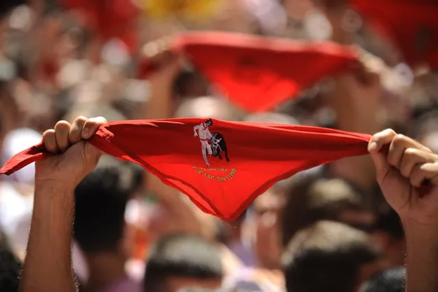 Revelers hold up traditional red neckties as tens of thousands of people packed Pamplona's main square in Pamplona, northern Spain on Saturday, July 6, 2013 to celebrate the start of Spain's most famous bull-running festival with the annual launch of the “chupinazo” rocket. Perhaps best glorified by Ernest Hemingway's 1926 novel “The Sun Also Rises”, the San Fermin festival is known around the world for the daily running of the bulls. (Photo by Alvaro Barrientos/AP Photo)