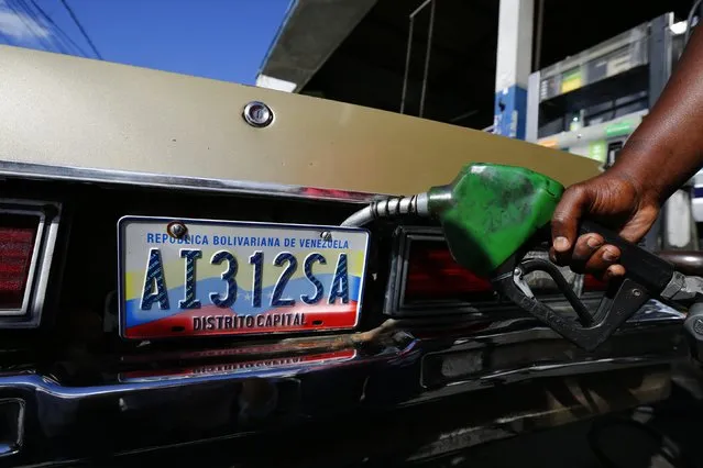 A worker fills up a car with fuel at a gas station in Caracas, January 12, 2015. (Photo by Jorge Silva/Reuters)