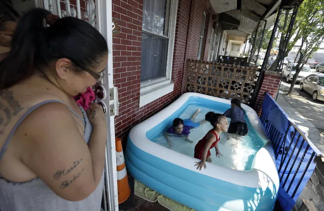 Luz Pratts, left, watches her daughters Karina, 11, Amarilys, 9, background, play with Laylana, 3, in an inflatable pool on the front porch as they keep cool in the West Kensington neighborhood of Philadelphia, Monday July 2, 2018. The National Weather Service has issued an excessive heat warning through Tuesday in the Philadelphia area with oppressive temperatures expect to last through the Fourth of July holiday. (Photo by Jacqueline Larma/AP Photo)