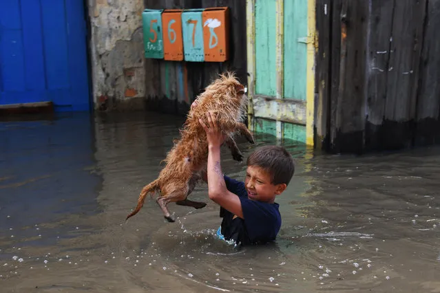 A boy holds his dog above water in the city of Chita hit by floods, the state of emergency declared in the Transbaikal Territory, Russia as the Chita River bursts its banks on July 10, 2018. (Photo by Yevgeny Yepanchintsev/TASS)