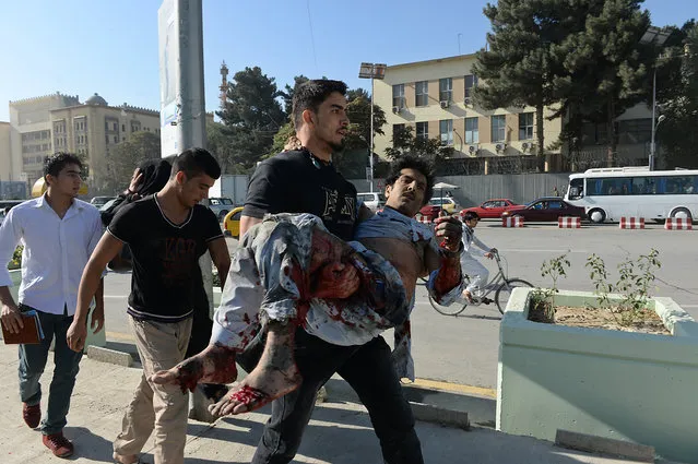 An Afghan man carries a wounded man at the site of a suicide attack in Kabul on September 16, 2014. A large blast ripped through central Kabul on September 16, shaking buildings and setting off the siren alert at the US embassy as emergency vehicles raced through the streets to assess the damage. (Photo by Shah Marai/AFP Photo)