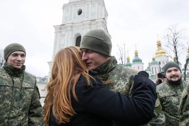 A woman embraces a member of the newly created Ukrainian interior ministry battalion “Saint Maria” after a ceremony before they head to military training, in front of St. Sophia Cathedral, in Kiev, February 3, 2015. (Photo by Valentyn Ogirenko/Reuters)